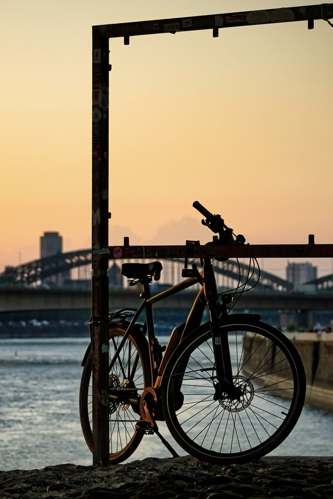 Fahrrad am Rheinufer in Köln bei Sonnenuntergang – Radfahren im Rheinland
